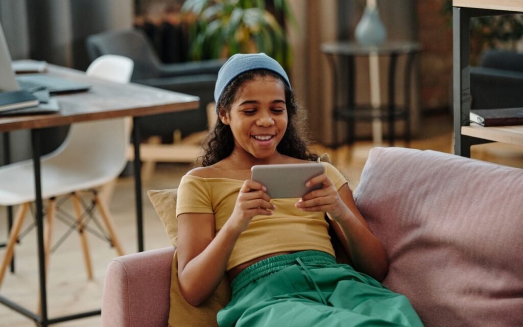 Jeune fille qui regarde une émission sur une tablette, au salon